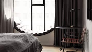 Un dormitorio con una cama, un ventanal redondo, una mesa y una silla.