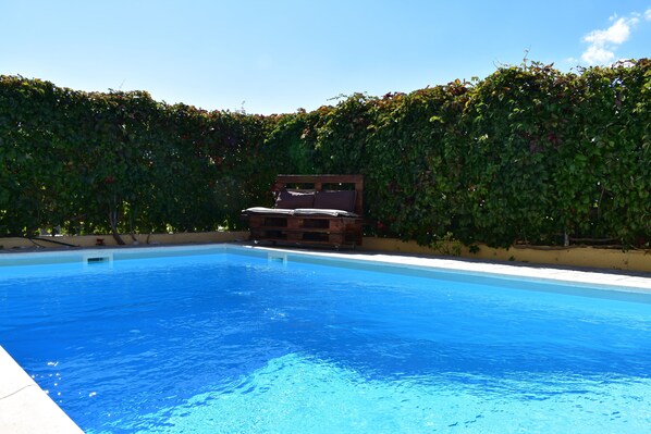 Una piscina al aire libre, sillones reclinables de piscina