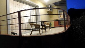 A balcony with a metal railing, a wicker chair, a small table with a bottle, and a potted plant. - Helen's Villa (Rafina-Pikermi)