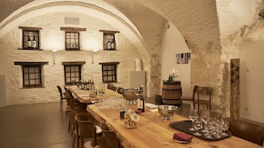 A rustic dining room with a long wooden table set for a meal, multiple wine bottles, glasses, and a candle holder. - Klosterhotel Kreuz (Metzerlen)