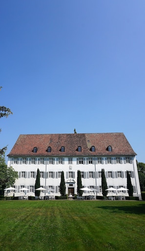 A large, white building with a red-tiled roof, multiple windows, and a symmetrical facade. - Klosterhotel Kreuz (Metzerlen)