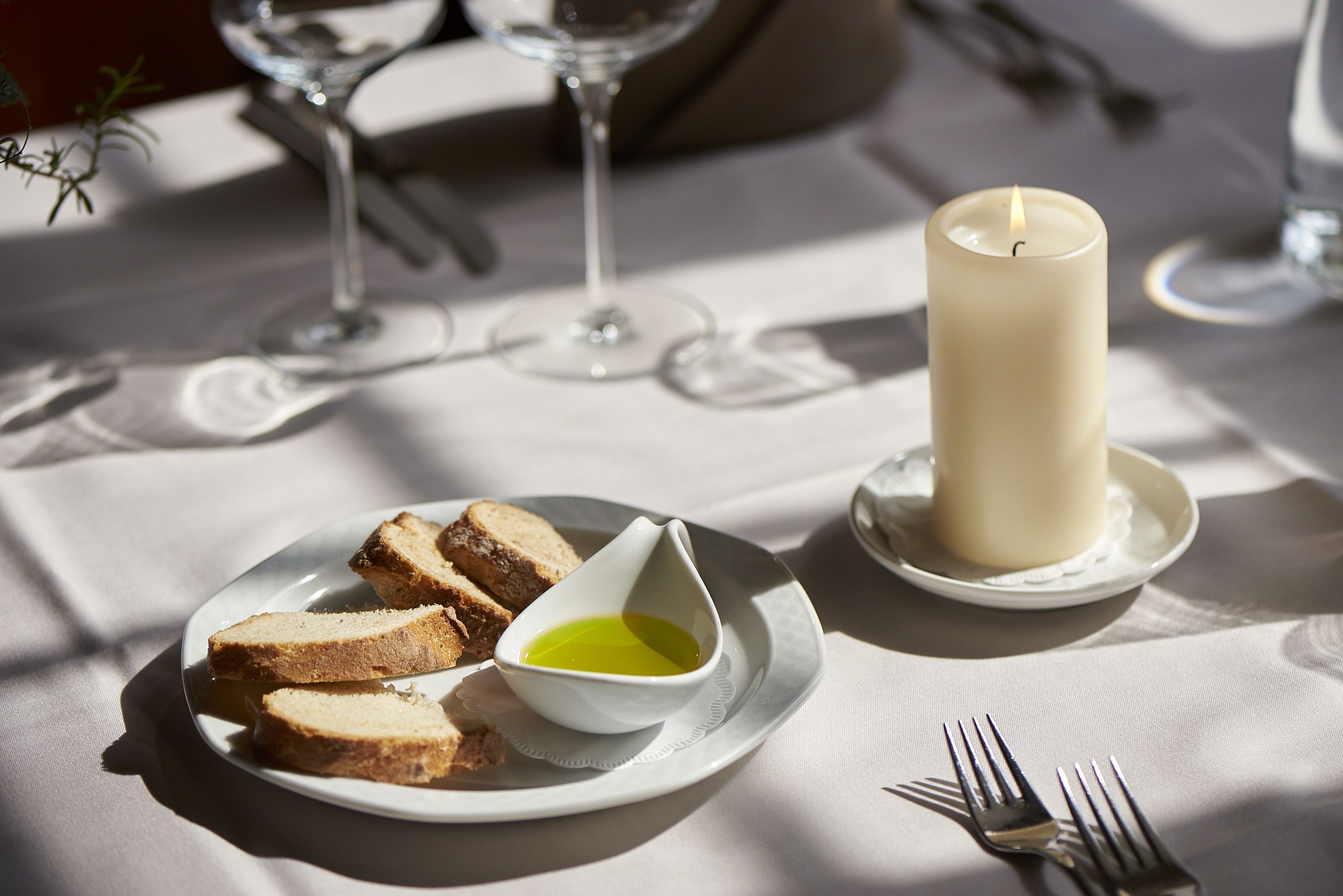 Ein gedeckter Tisch mit Brot, einer Kerze und einer kleinen Schale Öl.