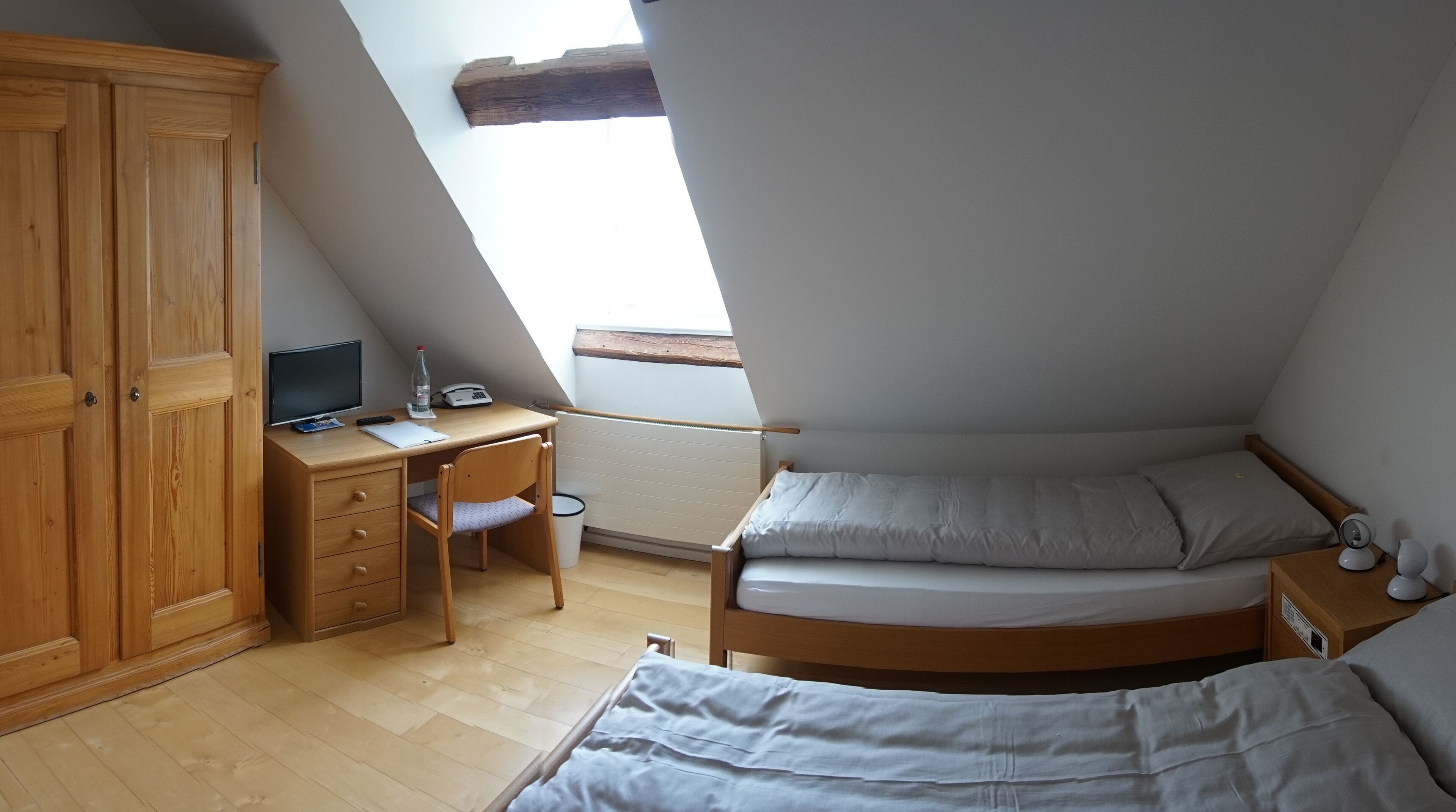 Un dormitorio con escritorio de madera, una silla, una cama y un armario.