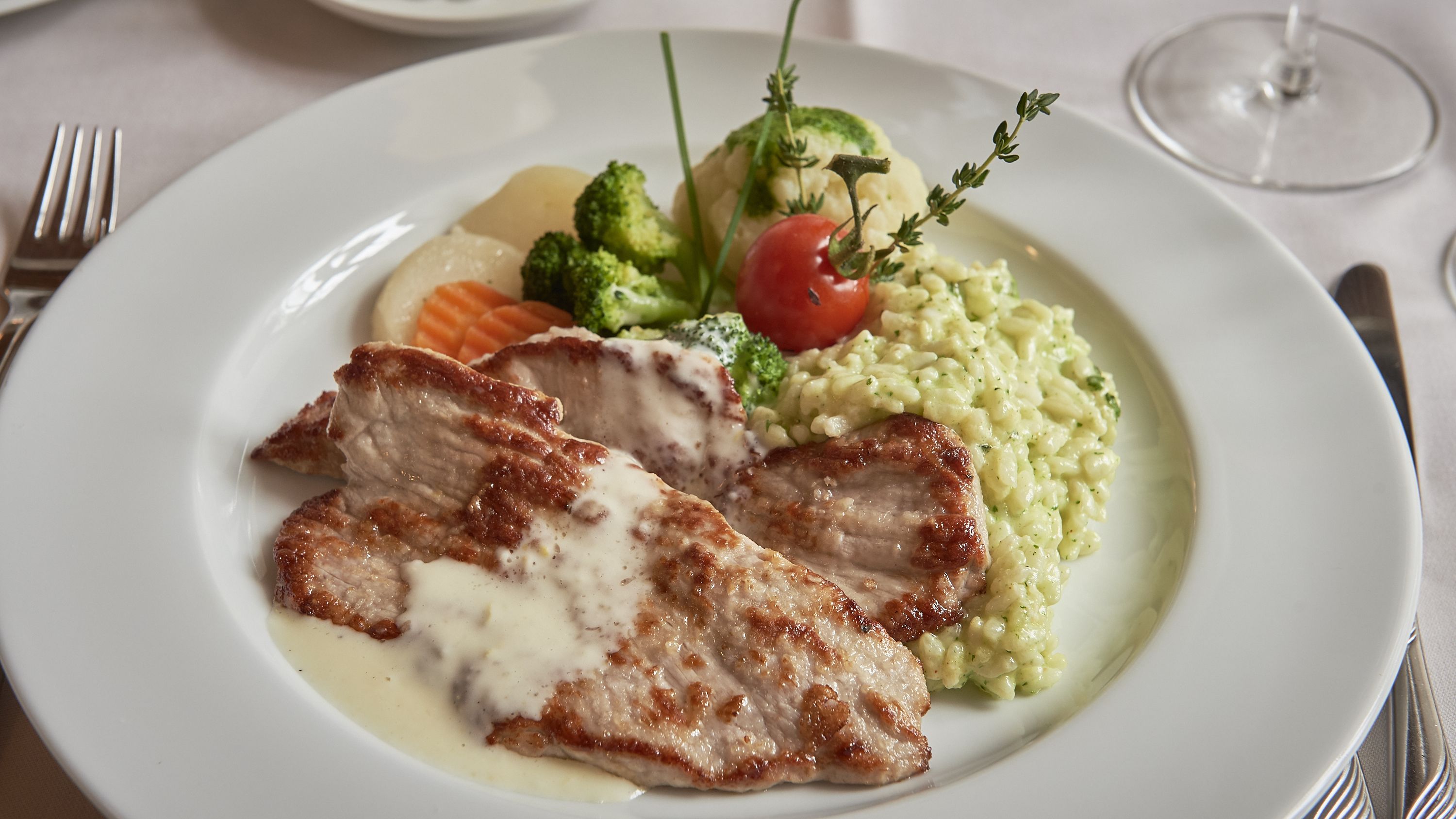Ein Teller mit Fleisch, Gemüse und einer cremigen Beilage.