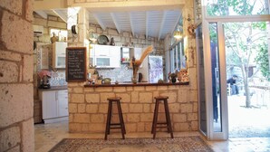 A rustic kitchen with a chalkboard menu, wooden stools, and a large window overlooking a garden. - Kavalalı Butik Otel (Cesme)