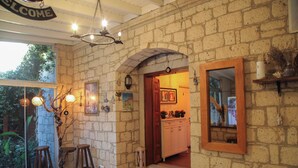 A rustic interior with a stone wall, wooden door, and a 'WELCOME' sign. - Kavalalı Butik Otel (Cesme)