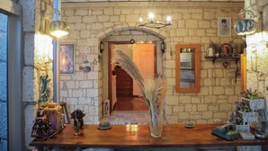 A rustic interior with a stone wall, wooden floor, a chandelier, a wooden reception desk, and a mirror. - Kavalalı Butik Otel (Cesme)