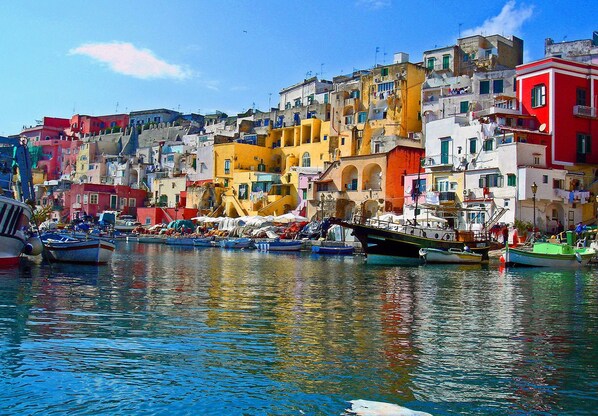 Un pueblo costero con edificios coloridos y barcos amarrados a lo largo del paseo marítimo.