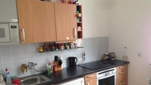 A compact kitchen with wooden cabinets, a dishwasher, an oven, and a sink. - Zimmer in Herne (Herne)