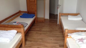 A room with two wooden bunk beds, a wooden wardrobe, and a door leading to another room. - Zimmer in Herne (Herne)