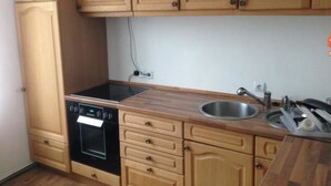 A kitchen with wooden cabinets, a built-in oven, a sink, and a countertop. - Zimmer in Herne (Herne)
