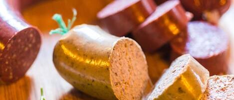 Sliced sausage and a whole sausage on a wooden surface with parsley leaves.