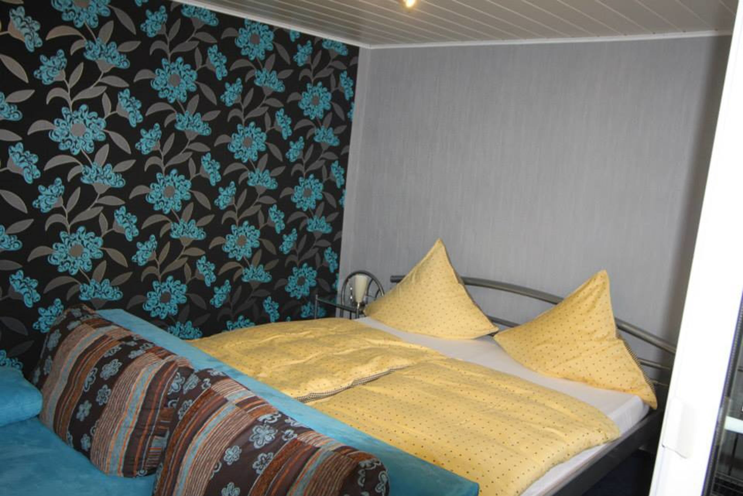 A room with a bed, a patterned wall, and a window.
