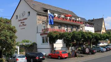 Un edificio con un letrero de restaurante, una bandera y coches estacionados.