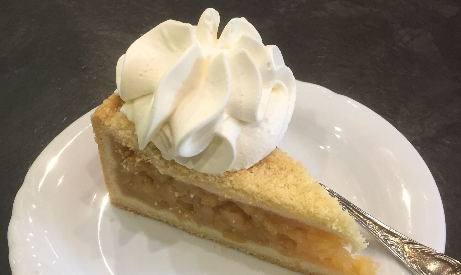 Una porción de pastel con cobertura cremosa sobre un plato blanco.