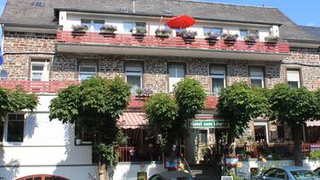 A hotel with a stone facade, red balconies with flower boxes, and a sign reading "Hotel zum Löw".