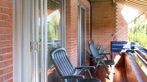 Un espacio de estar al aire libre con techo, sillas de metal y un banco azul.