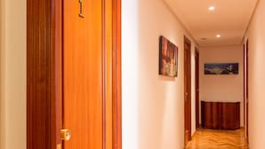 Un pasillo con puertas de madera, suelo estampado y obras de arte colgadas en la pared.