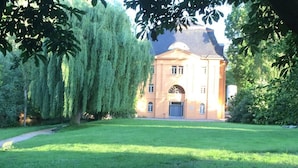 Ein Gebäude mit einer symmetrischen Fassade, einem zentralen Eingang und einem gepflegten Rasen drumherum.
