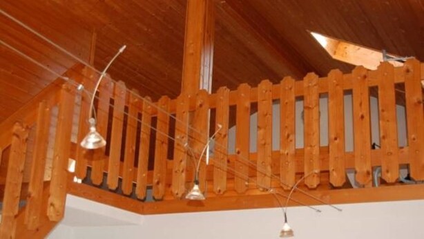 A wooden balcony with a railing and pendant lights. - Herrmanns - Ferienhaus (Zandt)
