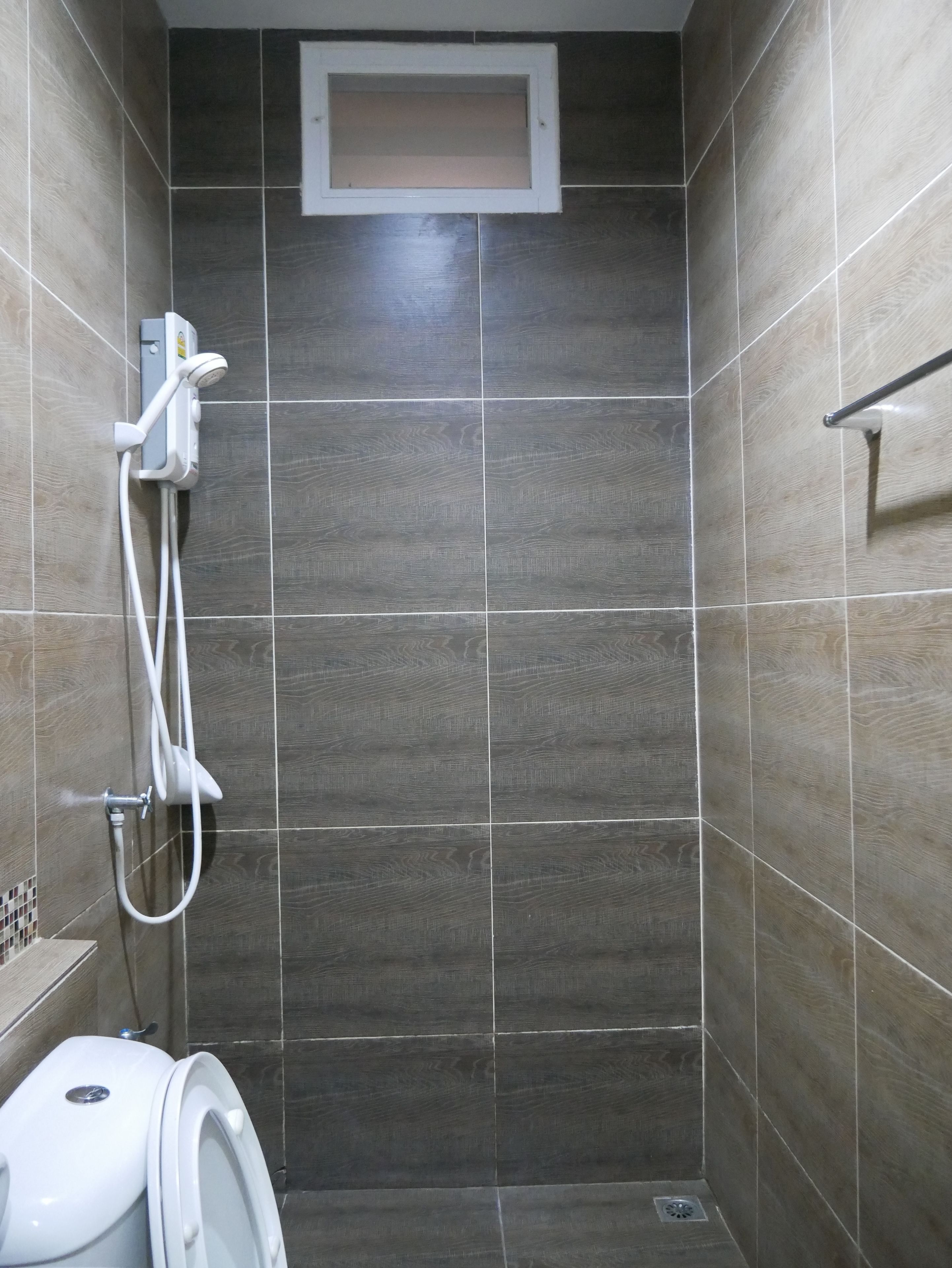 A small, tiled shower area with a toilet and a showerhead.