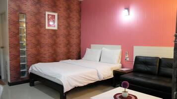Un dormitorio con cama, mesita de noche, sofá de cuero negro y una mesa de centro blanca con un objeto decorativo.