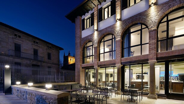 Un edificio con patio, mesas al aire libre y un interior de restaurante a la vista.