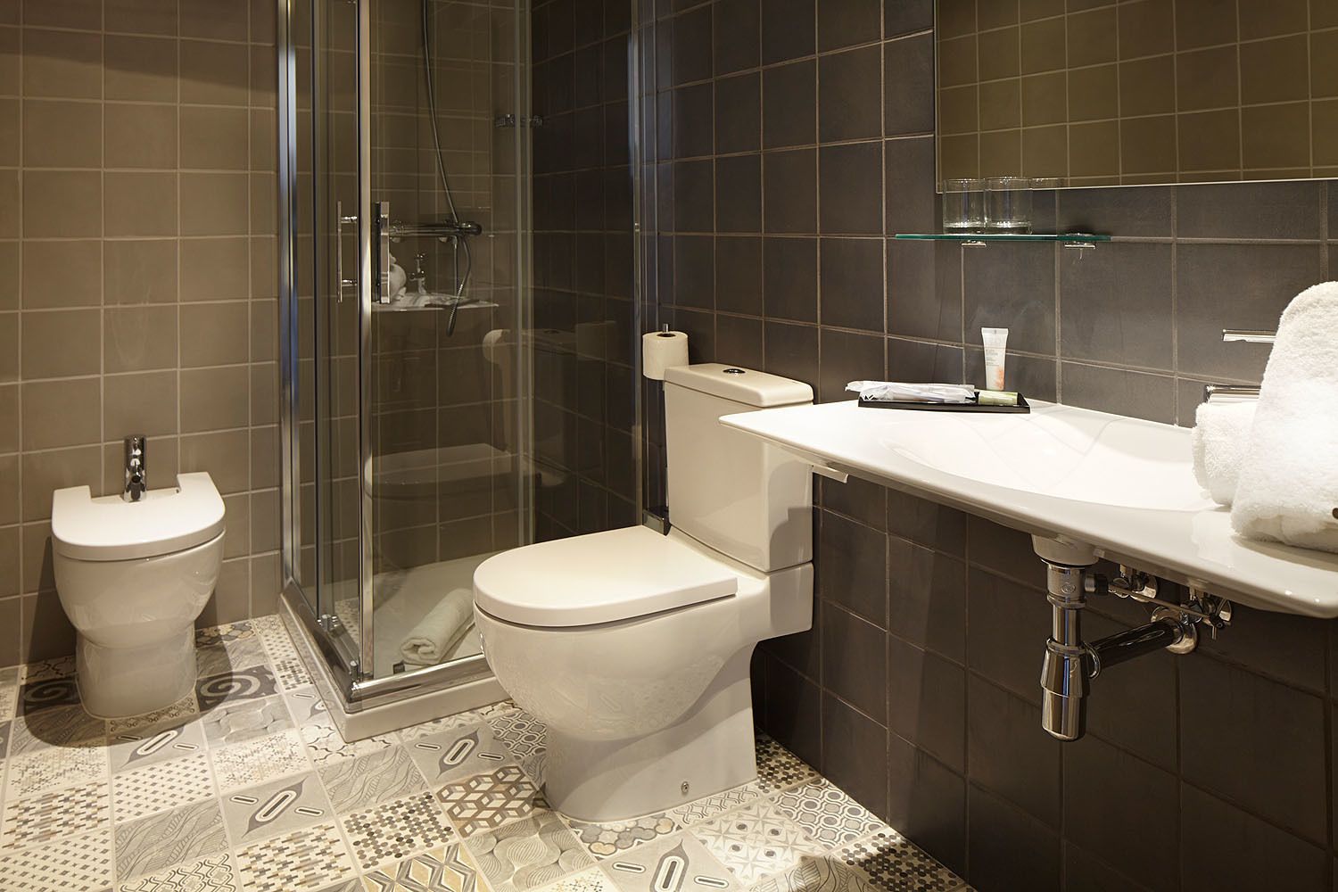 A modern bathroom with a toilet, bidet, and glass shower enclosure.