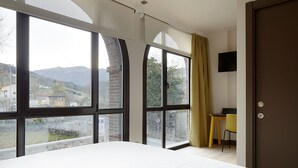 Un dormitorio con ventanas amplias, una cama, un escritorio y una silla.