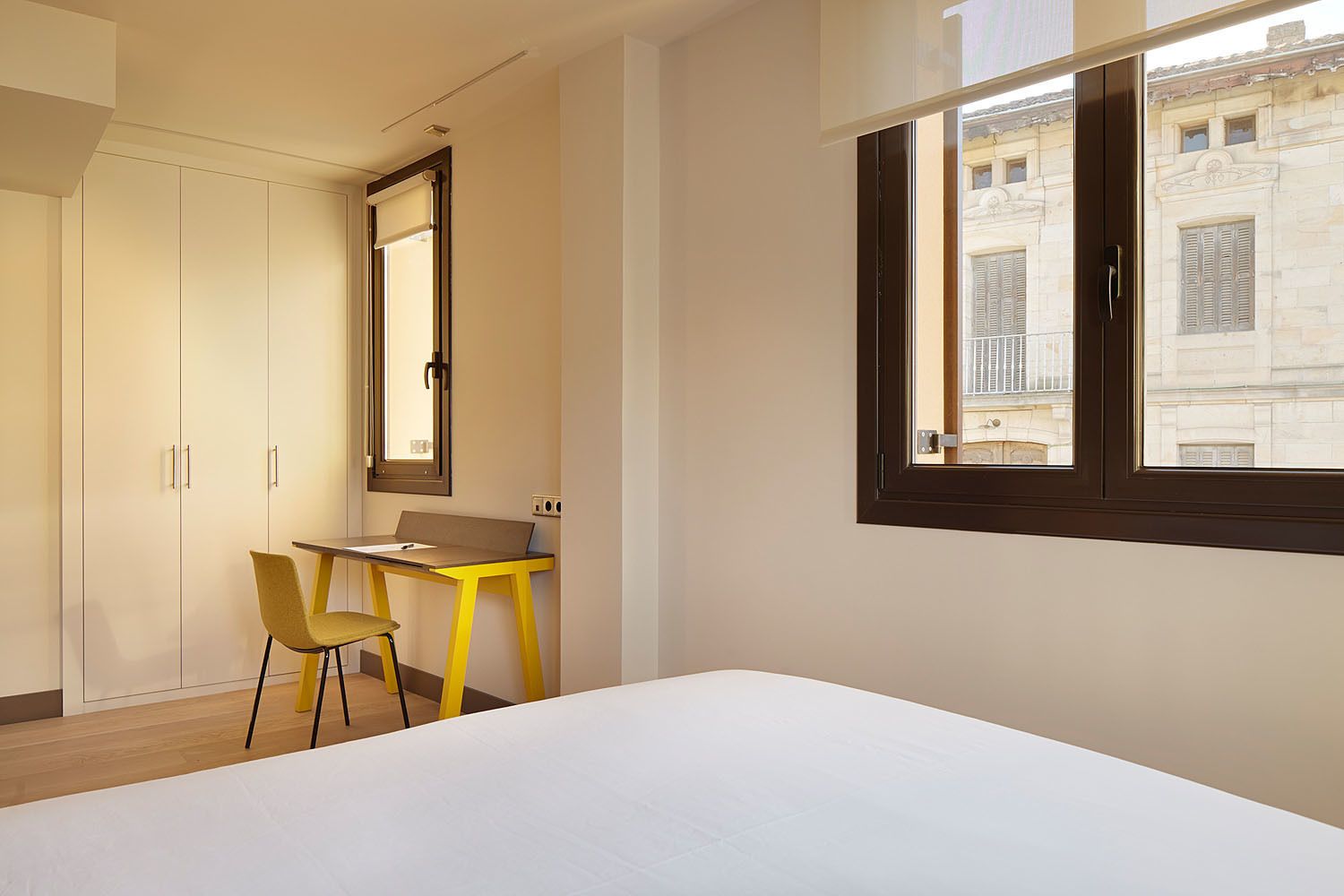 A bedroom with a bed, a desk, a chair, and a wardrobe.