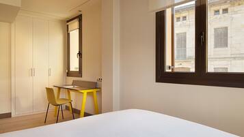 A bedroom with a bed, a desk, a chair, and a wardrobe.