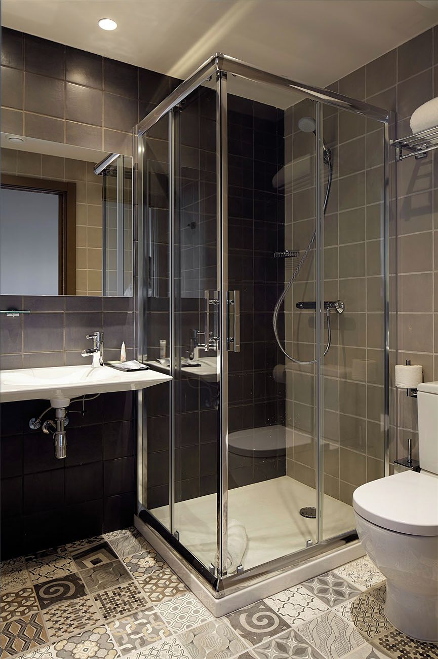 A modern bathroom with a glass-enclosed shower, a white sink, and a toilet.