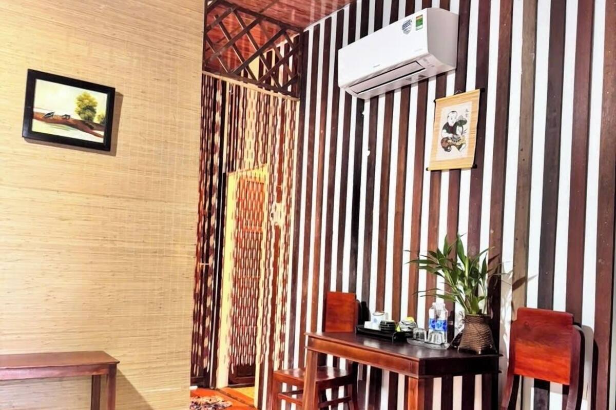 Un comedor con mesa y sillas de madera, pared a rayas y un equipo de aire acondicionado.