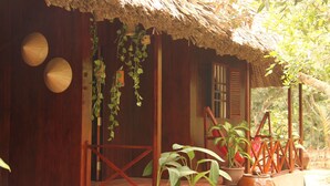 Una casa de madera con techo de paja, plantas en macetas y baranda de madera.