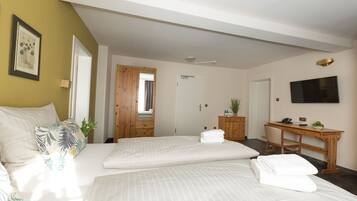A hotel room with two beds, a desk, a TV, and a door leading to another room.
