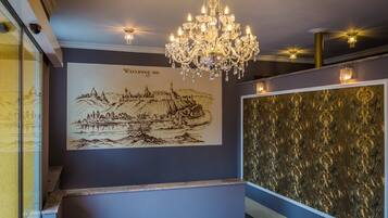 A grand chandelier, a detailed mural, and ornate wallpaper in a hotel lobby.