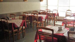 A restaurant with multiple tables and chairs, each covered with a red tablecloth. - Posada Galicia (Villa Maria)