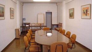 A conference room with a round table, orange chairs, a whiteboard, and framed artwork on the walls. - Posada Galicia (Villa Maria)