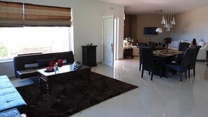 A modern living room with a sofa, coffee table, and dining area with chairs. - Elina Luxury Residence Villa (Chania)