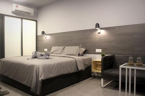 Un dormitorio moderno con una cama grande, mesitas de noche, una silla y una pequeña mesa con vasos.