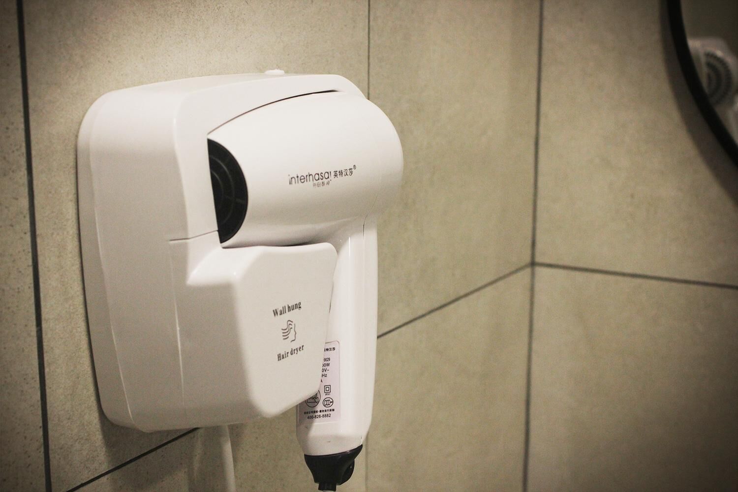 A wall-mounted hair dryer with a cord plugged in, labeled "interhasa!".