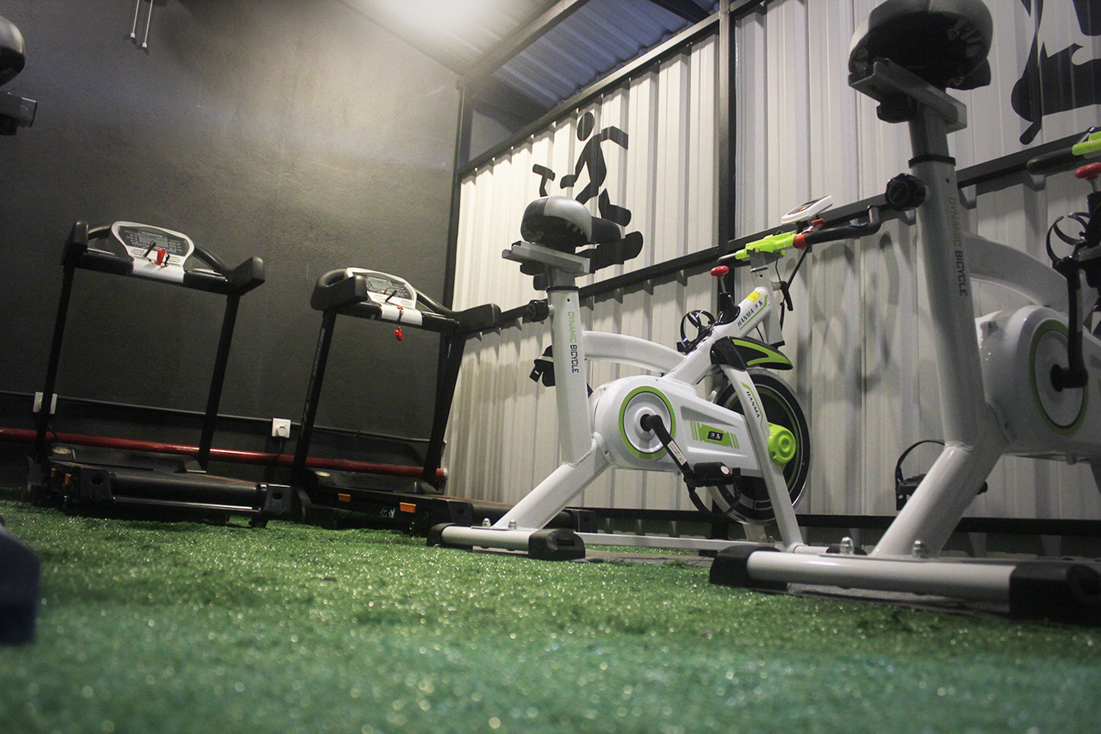 A gym with stationary bikes, treadmills, and exercise equipment on a green floor.
