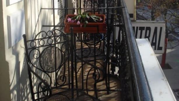 A balcony with a metal railing, a flower box, and a sign that reads "HOSTA CENTRAL". - Hostal Central (Zaragoza)