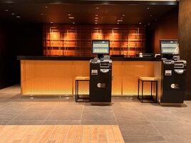 A reception desk with two monitors, a ticket machine, and a seating area.