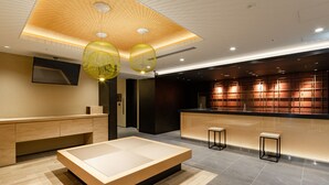 A modern hotel lobby with a large seating area, a reception desk, and a TV mounted on the wall. - The OneFive Kyoto Shijo (Kyoto)
