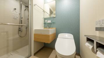 Un baño moderno con cabina de ducha de vidrio, inodoro blanco y tocador de madera con espejo.