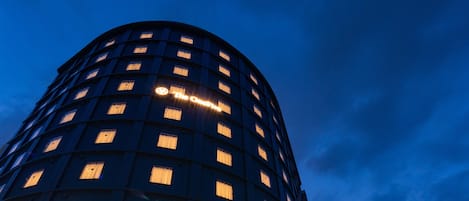 Un hotel alto y cilíndrico con una serie de ventanas distribuidas uniformemente en su fachada.