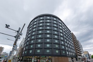 Een hotel met meerdere verdiepingen, een gebogen gevel, veel ramen en een duidelijke ingang met borden.