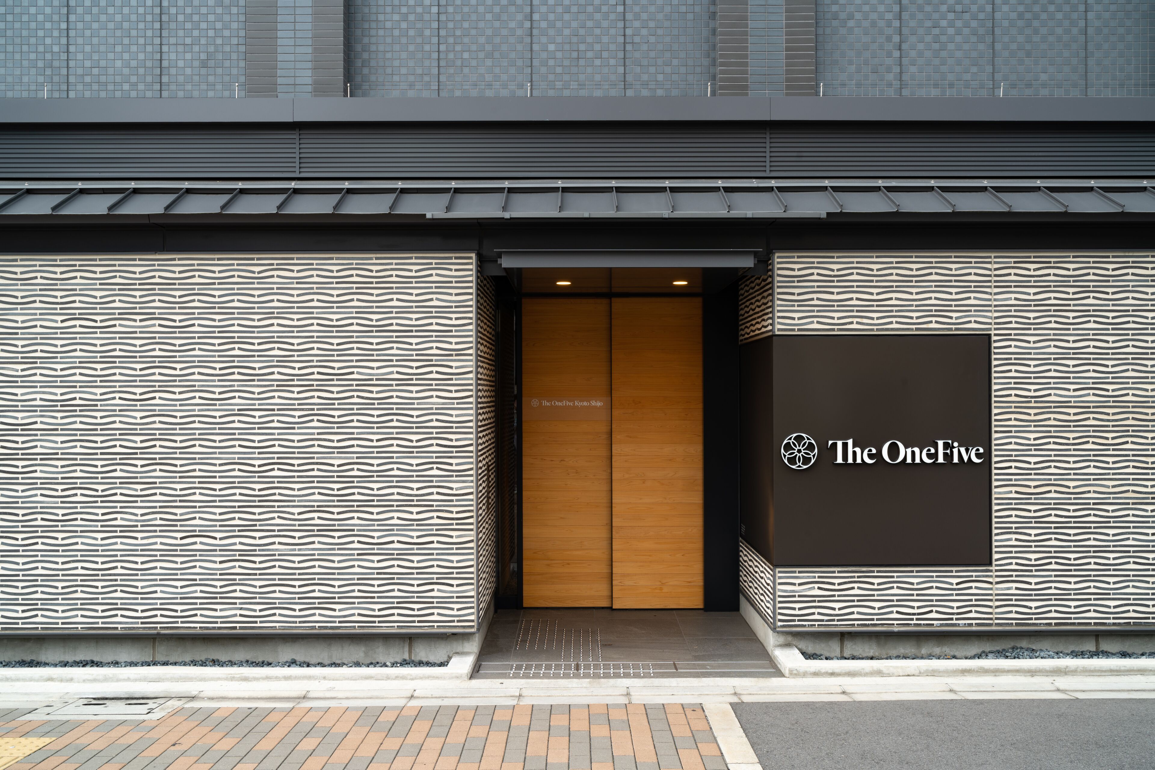 Una entrada de edificio moderna con fachada estampada y puerta de madera.