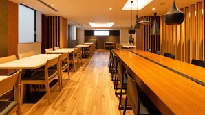 A modern restaurant with wooden tables and chairs, a long counter, and pendant lighting. - The OneFive Kyoto Shijo (Kyoto)